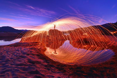 Person with wire wool against sky during sunset