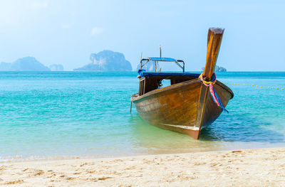 Boat moored on beach against sky