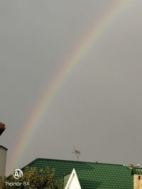 Low angle view of rainbow over building against sky
