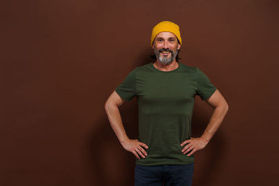 Portrait of man standing against yellow background