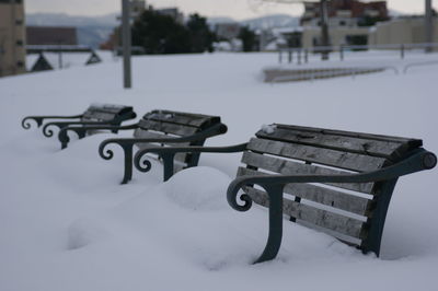 Empty bench in snow covered park during winter