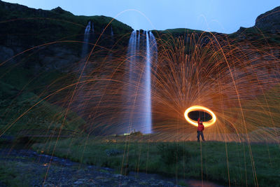 Blurred motion of man against illuminated lights at night