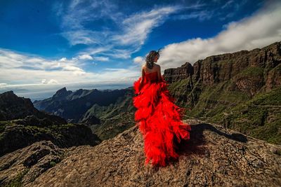 Woman with umbrella on mountain against sky
