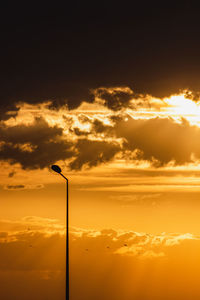 Low angle view of street light against dramatic sky