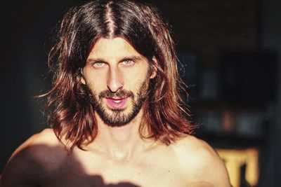 Close-up portrait of shirtless young man with long hair