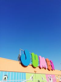 Low angle view of text on swimming pool against clear blue sky