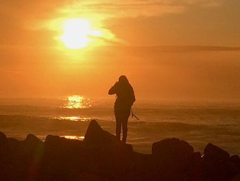 Silhouette of people on beach at sunset