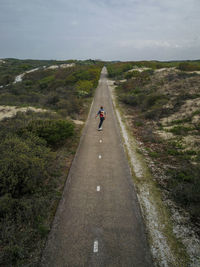 A man with long hair skating on a empty road in europe