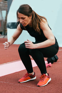 Full length of young woman exercising on sports track