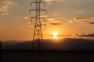 Silhouette electricity pylon against sky during sunset