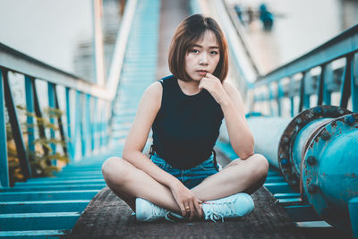 Portrait of woman sitting on footbridge