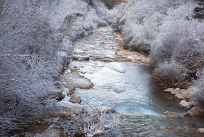 High angle view of river flowing amidst rocks during winter