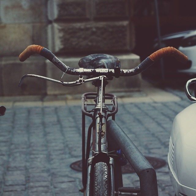 focus on foreground, metal, bicycle, close-up, indoors, transportation, mode of transport, land vehicle, part of, handle, street, no people, day, metallic, cropped, wall - building feature, built structure, sunlight, architecture