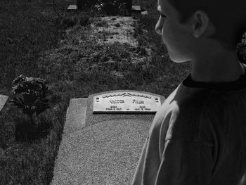 High angle view of boy at tombstone in cemetery