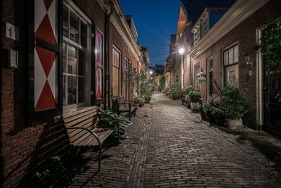 Walkway amidst buildings against sky at night