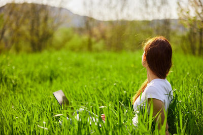 Rear view of woman sitting on grassy field