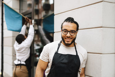 Portrait of male barber with eyeglasses outside hair salon