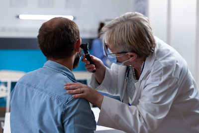 Doctor examining patients ear in clinic
