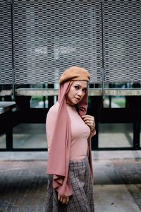 Portrait of woman standing against brick wall