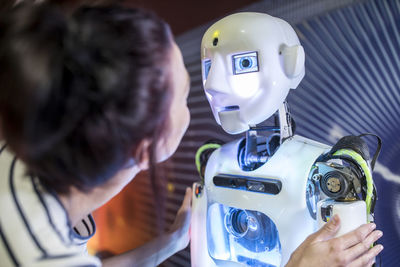 Tech developer looking at human robot in workshop