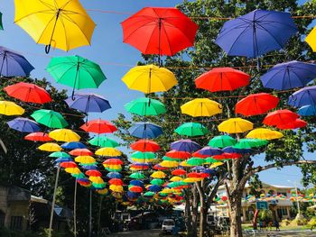 Low angle view of multi colored umbrellas hanging against sky