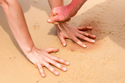 Cropped image of hands playing with sand at beach