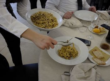 Low section of waiter serving pasta in bowl at restaurant