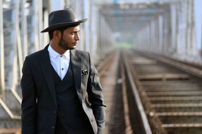 Man looking away while standing on railroad track