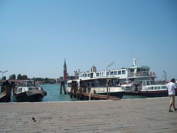 Boats in harbor against clear blue sky
