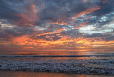 Scenic view of sea against cloudy sky at sunset