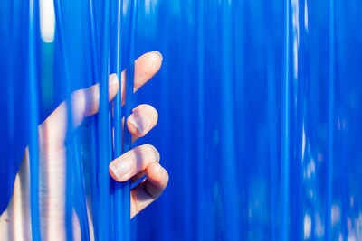 Cropped hand of person holding blue straws