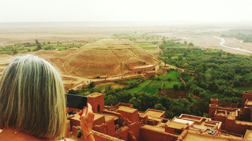 Rear view of woman sitting on landscape against clear sky