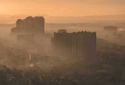 Buildings in city against sky during sunset