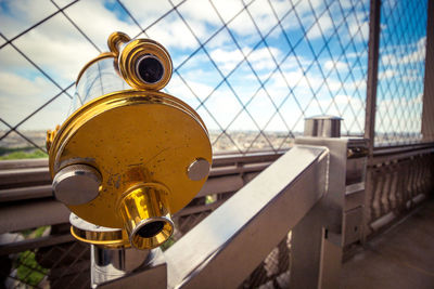 Close-up of yellow metal railing against sky