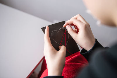 Hands make a card with a heart for valentine's day with red threads