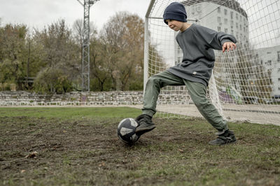 Boy in knit hat playing soccer at sports field