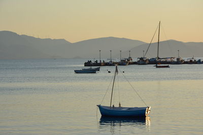 Sailboats sailing in sea against sky during sunset