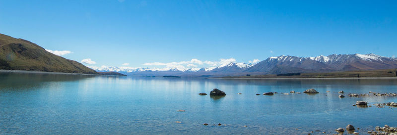 Scenic view of lake and mountains against blue sky