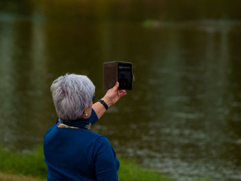 Woman photographing lake through mobile phone