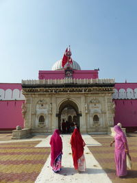 People in front of historic building against clear sky