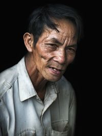 Close-up of senior man against black background