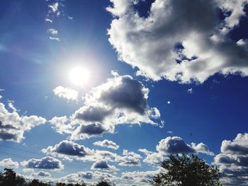 Low angle view of sun shining through clouds