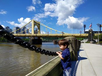 Boy standing on footpath by roberto clemente bridge over allegheny river