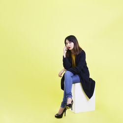 Young woman sitting against wall