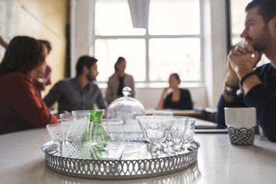 Empty drinking glasses in tray with business people discussing at conference table