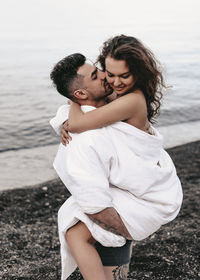 A diverse of lovers a man and a woman embrace under a blanket on the ocean at night outdoor