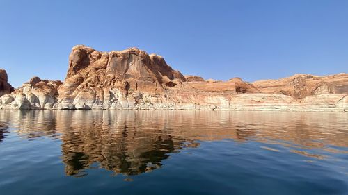 Rock formations in water against clear blue sky