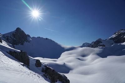 Scenic view of snowcapped mountains against blue sky