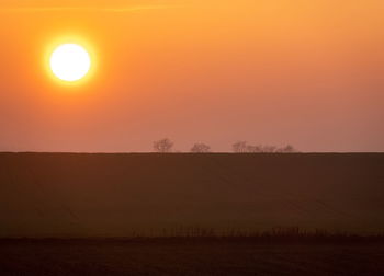 Scenic view of silhouette field against sky during sunset