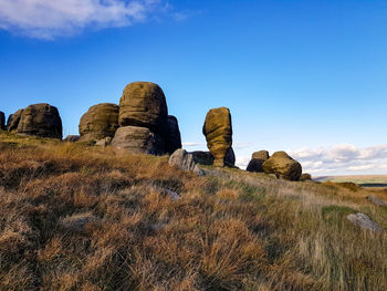 Low angle view of rock formations on field against sky